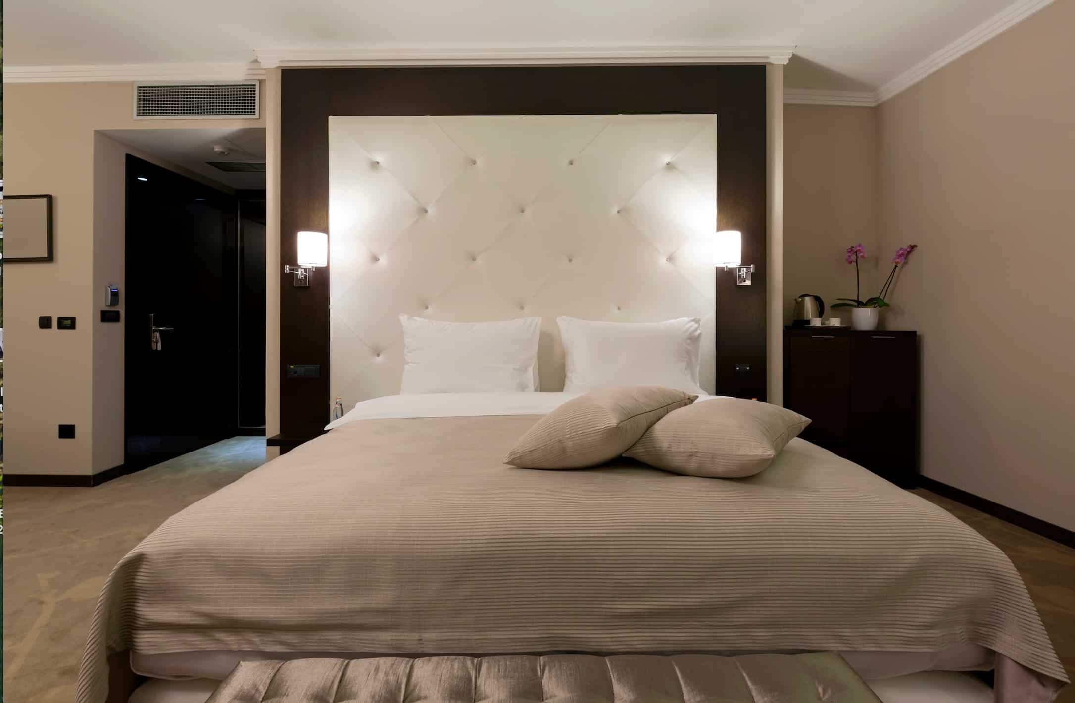 Hotel headboard featuring upholstered padded design with integrated wall lights for modern hotel bedrooms.