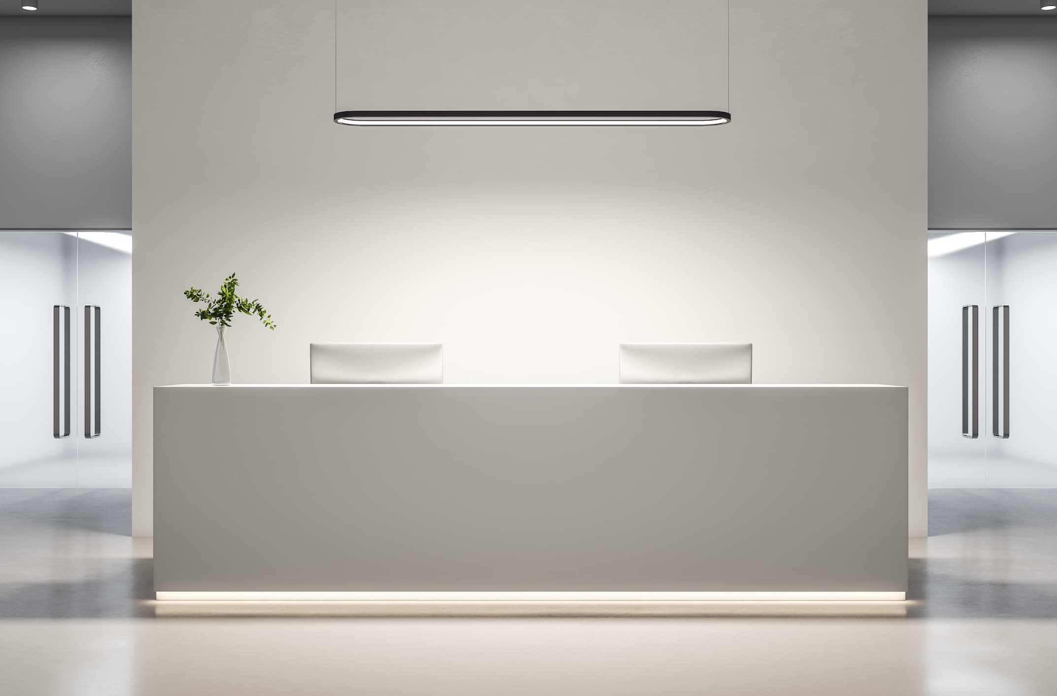 Minimalist hotel reception desk with clean white surfaces, soft lighting, and modern pendant fixture.