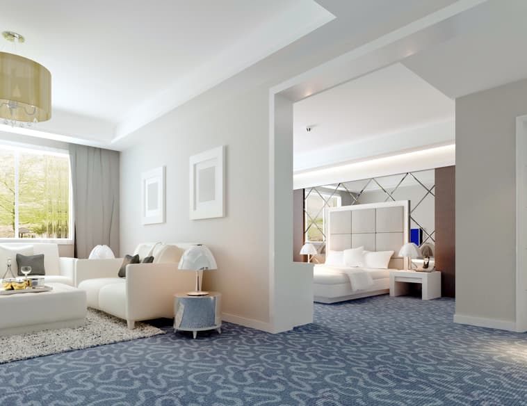 Contemporary hotel suite with wooden wall panels, sectional sofa, and round coffee table