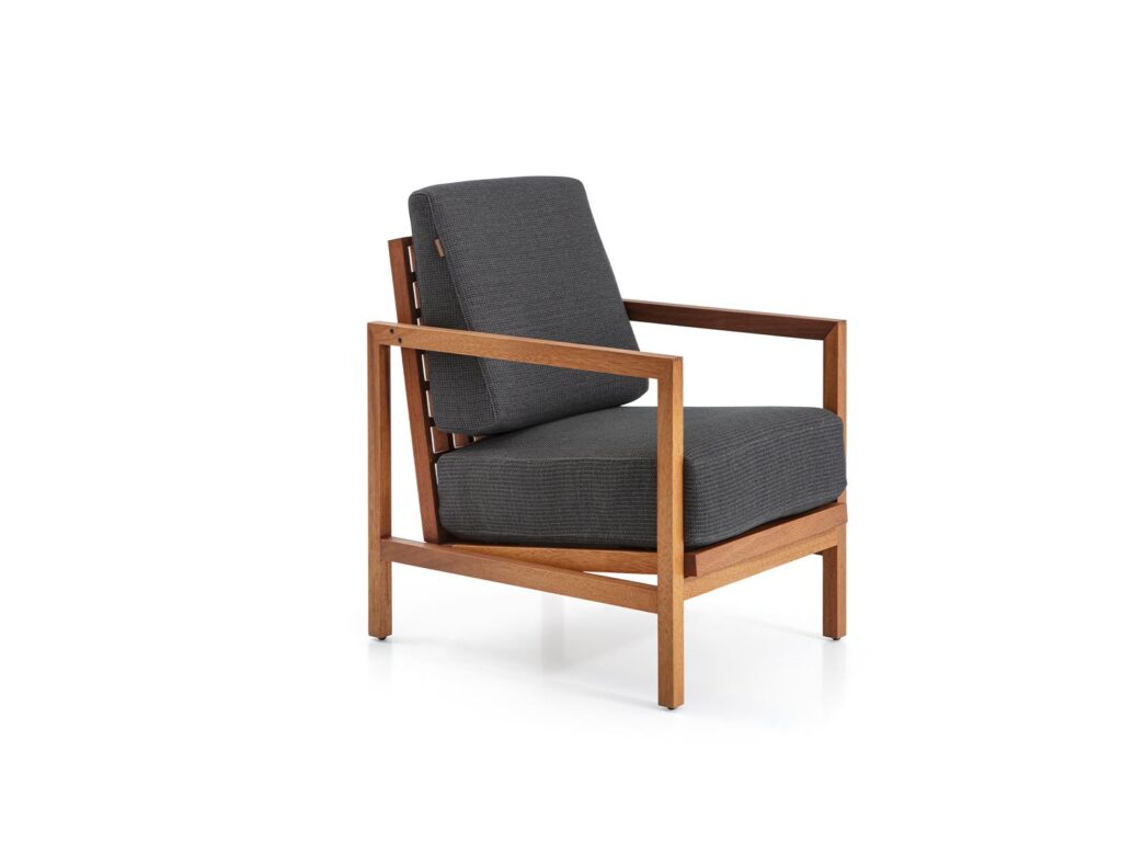 Minimalist lounge chair with dark fabric upholstery, wooden arm frame, and modern hotel design.