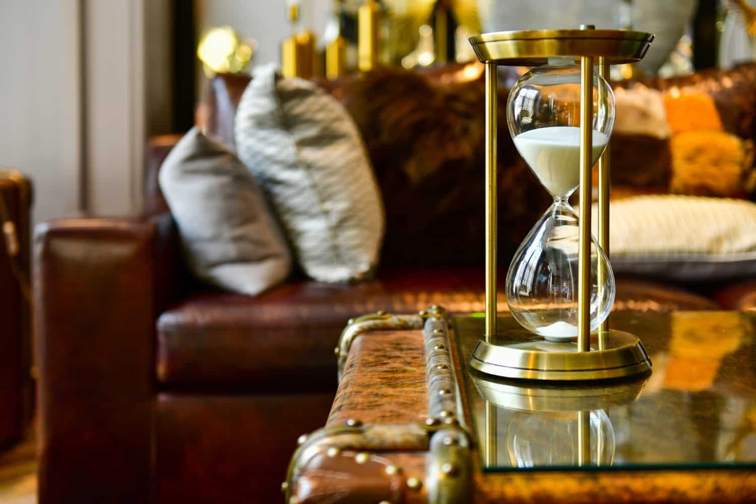 Hotel furniture lead time planning — hourglass on hotel lobby coffee table with upholstered seating