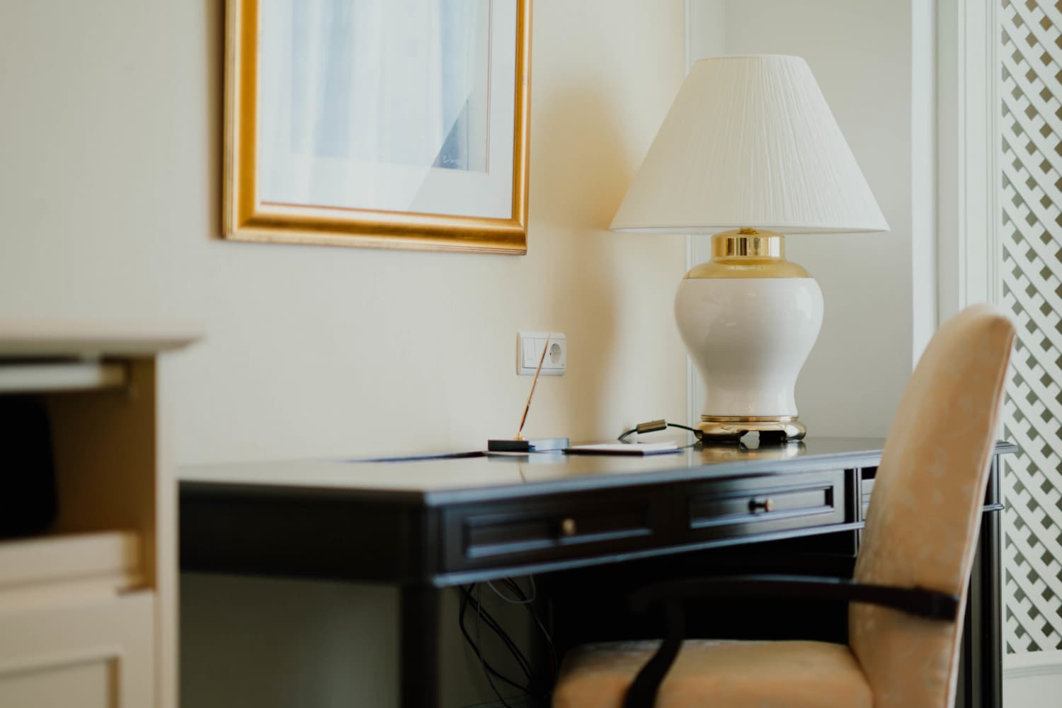 Hotel writing desk specification — dark lacquered hotel desk with drawer unit, desk lamp and upholstered chair beside window
