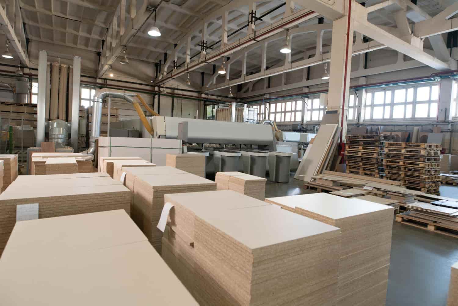 Turkish hotel furniture factory direct — large production hall with MDF and plywood panel stacks ready for CNC cutting